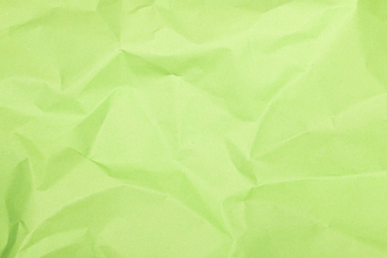 A close-up of crumpled green paper texture with natural folds and creases.